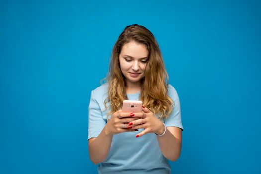 Smiling young woman girl using mobile phone and typing sms message to a friends. Chatting with a friends via messengers. People lifestyle concept. Mock up copy space