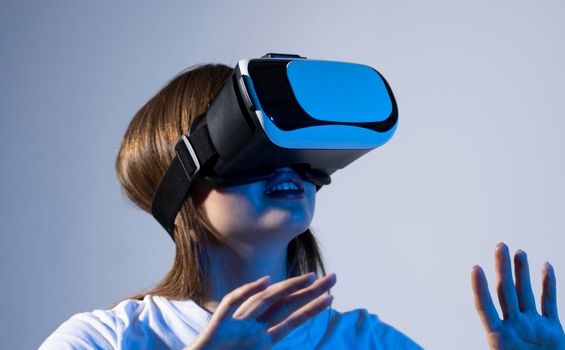 Young brunette woman wearing a virtual reality headset goggles and playing a game with a friends in metaverse. Future technology concept