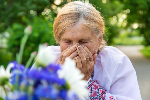 The old woman is allergic to flowers. Selective focus. Nature.