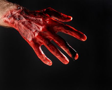 Close-up of a male hand stained with blood on a black background