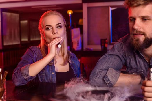 A man and woman smoking electronic cigarette in a vape bar. Vape shop