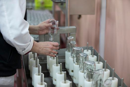 A row of glass bottles on a conveyor belt for the production of alcoholic beverages.