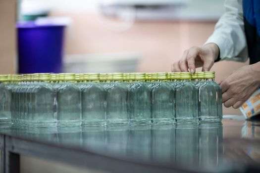 A row of glass bottles on a conveyor belt for the production of alcoholic beverages.