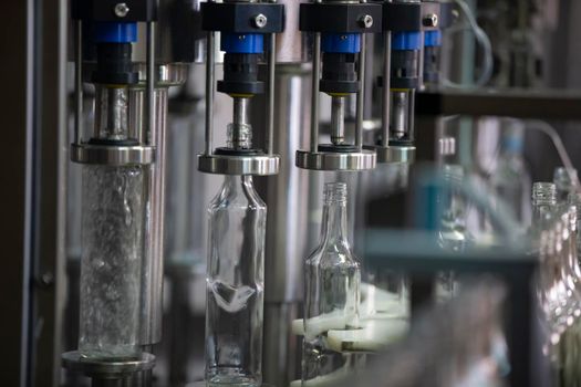 A long row of glass bottles on a conveyor belt. Production of alcoholic beverages.