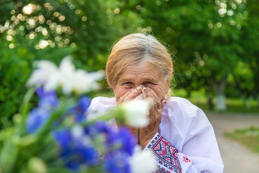 The old woman is allergic to flowers. Selective focus. Nature.