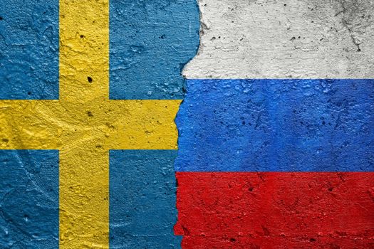 Sweden and Russia - Cracked concrete wall painted with a Swedish flag on the left and a Russian flag on the right