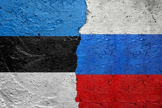 Estonia vs Russia - Cracked concrete wall painted with a Estonian flag on the left and a Russian flag on the right