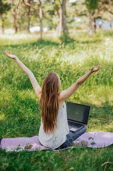 the girl sits outdoors and works at a laptop. she rejoices at the end of the working day. freelance. selfeducation. the concept of remote learning and outdoor work