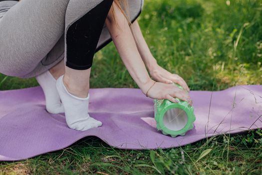 Woman practicing yoga and meditating outdoors. Girl preparing material for practice class in garden. Female happiness and yoga concept. During the quarantine due to the spread of the coronavirus