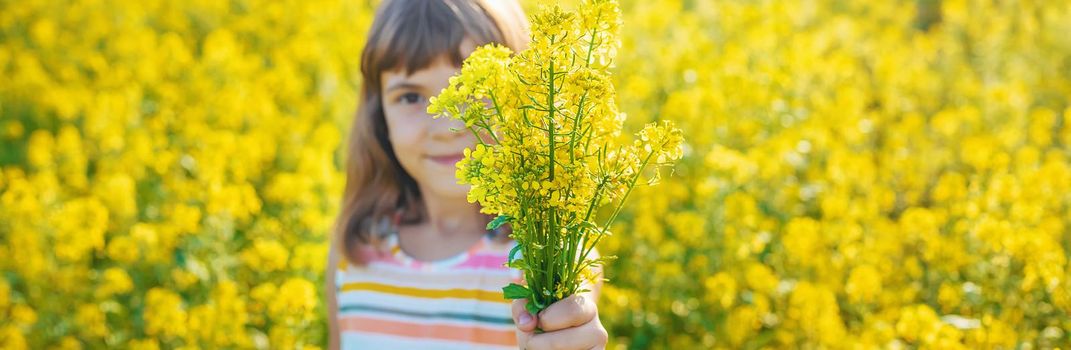 A child in a yellow field, mustard blooms. Selective focus.