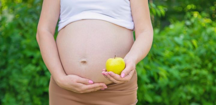 Pregnant woman with an apple in her hands. Selective focus. food.