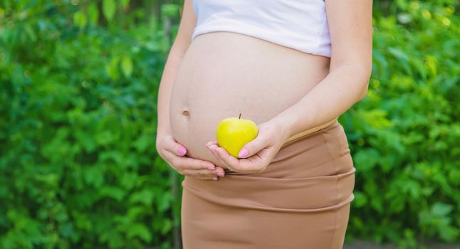 Pregnant woman with an apple in her hands. Selective focus. food.