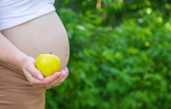 Pregnant woman with an apple in her hands. Selective focus. food.