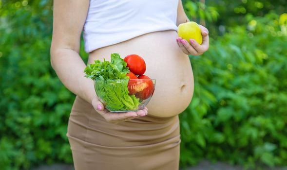 A pregnant woman with vegetables in her hands. Selective focus. food.