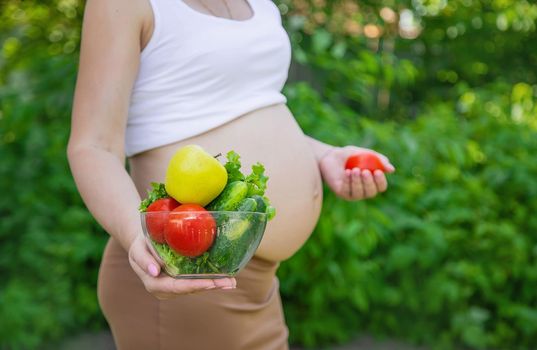 A pregnant woman with vegetables in her hands. Selective focus. food.