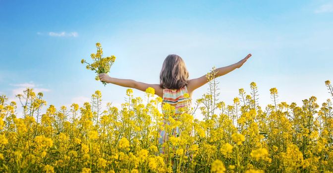 A child in a yellow field, mustard blooms. Selective focus. nature.