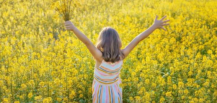 A child in a yellow field, mustard blooms. Selective focus. nature.