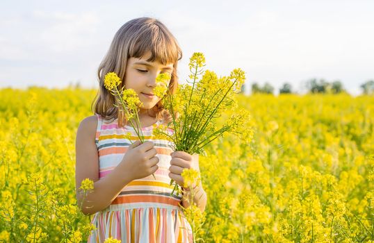 A child in a yellow field, mustard blooms. Selective focus..