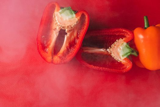 SWEET, fresh RED PEPPER ON A RED BACKGROUND, cut in half, thick smoke around. proper nutrition. fresh vegetables