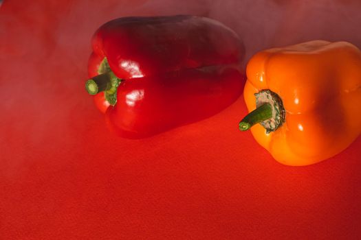 SWEET RED AND ORANGE PEPPERS ON A RED BACKGROUND.