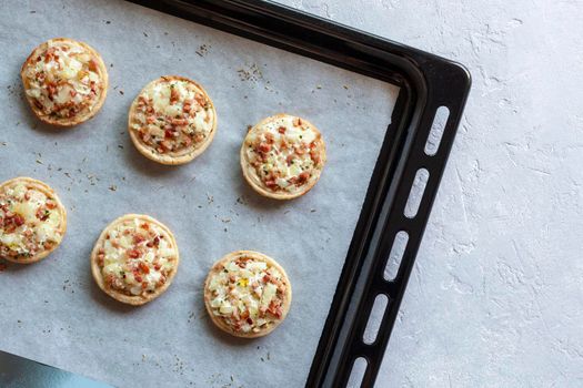 mini Flammekueche, or tarte flambee, french specialty, on the paper on the oven-tray