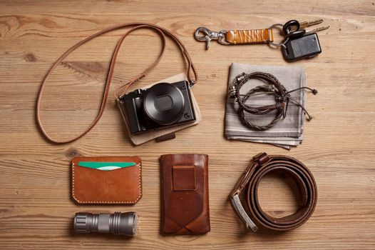 closeup vintage style of digital mirrorless camera with leather strap and other EDC for men.