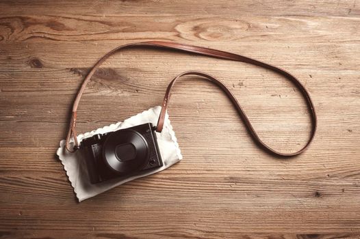 vintage style of digital mirrorless camera with leather strap isolated on wooden background