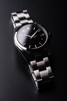 closeup luxury automatic wristwatch for men with black dial and stainless steel bracelet.