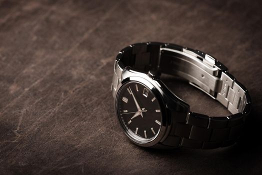 closeup luxury automatic wristwatch for men with black dial and stainless steel bracelet.