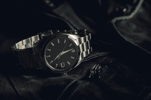 closeup luxury automatic wristwatch for men with black dial and stainless steel bracelet.