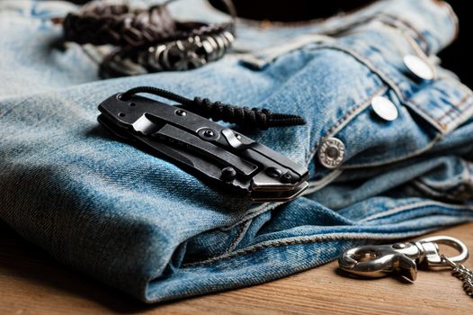 folding knife and jeans. closeup stainless steel pocketknife with blackwash finish on blade and handle.