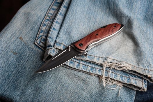 stainless steel folding knife with wooden handle and other everyday carry (EDC) items for men. closeup at folding knife. 