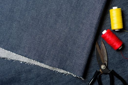 closeup indigo denim fabric texture with dressmaker's tools, material for jeans and other garment.