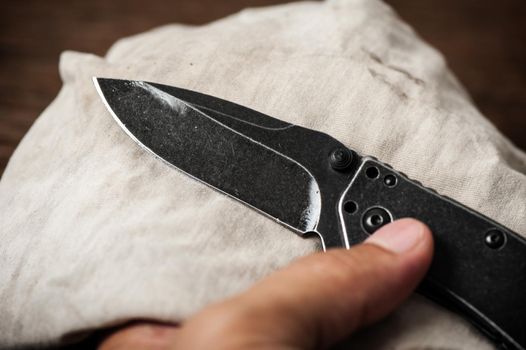 The man oiling his pocket knife. Pocket knife care and maintenance concept.