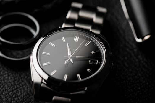 closeup luxury automatic wristwatch for men with black dial and stainless steel bracelet.