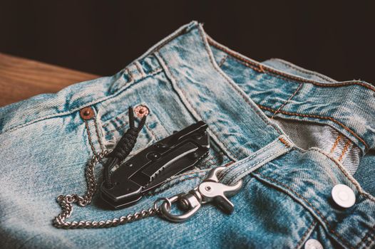 folding knife and jeans. closeup stainless steel pocketknife with blackwash finish on blade and handle.