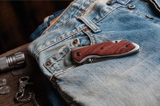 stainless steel folding knife with wooden handle and other everyday carry (EDC) items for men. closeup at folding knife. 