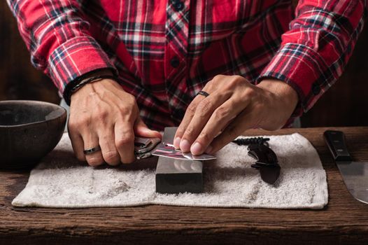 The man using whetstone to sharpening his pocket knife. Pocket knife care and maintenance concept.