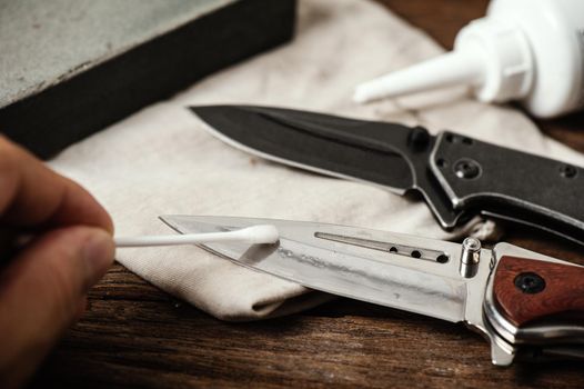 The man oiling his pocket knife. Pocket knife care and maintenance concept.