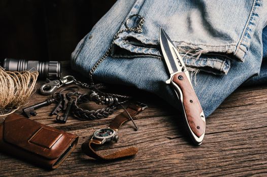 stainless steel folding knife with wooden handle and other everyday carry (EDC) items for men. closeup at folding knife. 