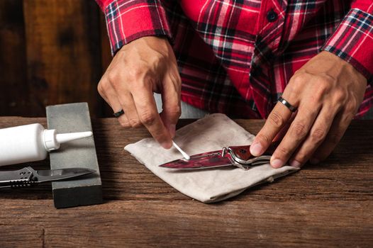 The man oiling his pocket knife. Pocket knife care and maintenance concept.