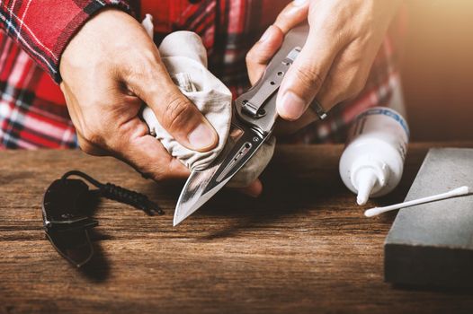 The man oiling his pocket knife. Pocket knife care and maintenance concept.