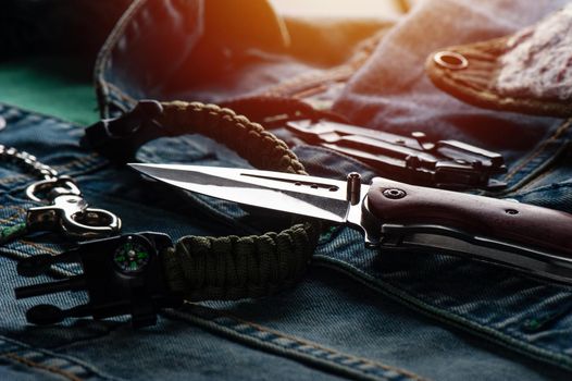 stainless steel folding knife and other everyday carry (EDC) items for men. closeup at folding knife. (low light and shallow depth of field)