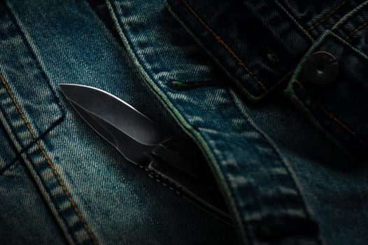 stainless steel folding knife over denim jacket
