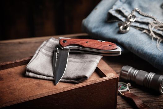 stainless steel folding knife with wooden handle and other everyday carry (EDC) items for men. closeup at folding knife. 