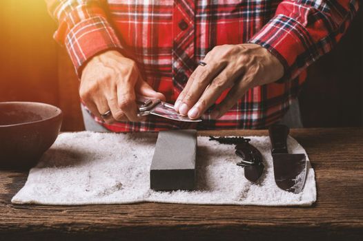 The man using whetstone to sharpening his pocket knife. Pocket knife care and maintenance concept.