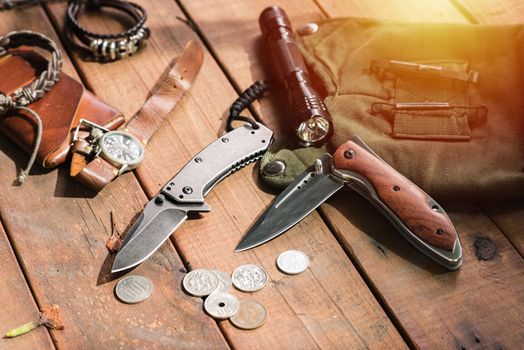 many men's items on wood plank, closeup at stainless steel folding knife.