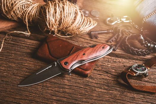 stainless steel folding knife with wooden handle and other everyday carry (EDC) items for men. closeup at folding knife. 