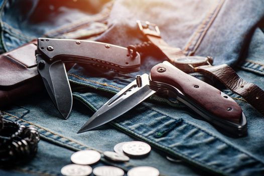 stainless steel folding knife with wooden handle and other everyday carry (EDC) items for men. closeup at folding knife. (low light and shallow depth of field)