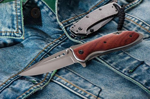 stainless steel folding knife with wooden handle isolated on Jeans.